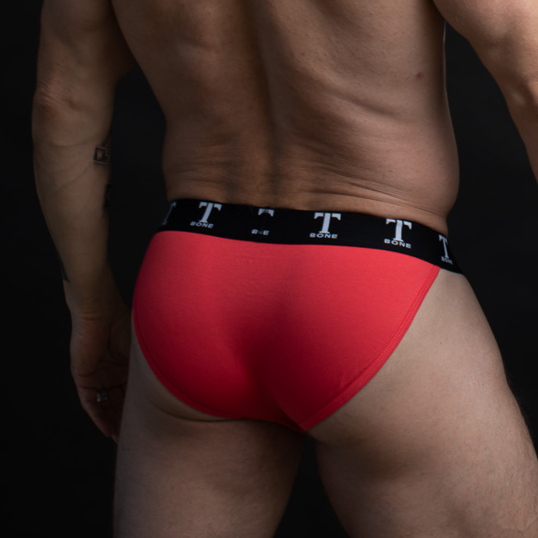Rear view of man in red brief underwear with waistband reading "TBONE"