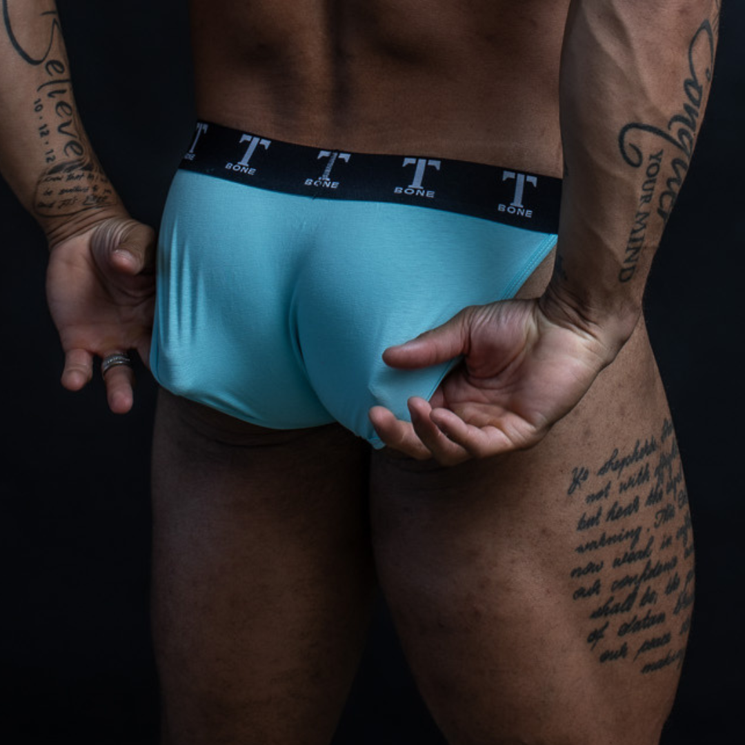 Rear view of man in blue brief underwear with waistband reading "T BONE" 